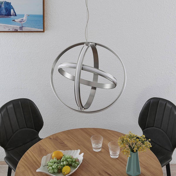 Moderne LED-Pendelleuchte im kugelförmigen Ring-Design aus Metall, hängend über einem runden Esstisch aus Holz in einem hellen Raum.