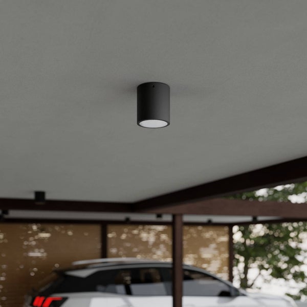 Schwarze, zylindrische Deckenanbauleuchte montiert an der Decke eines modernen Carports.