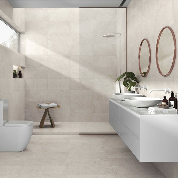 Modernes, helles Badezimmer mit großformatigen beigen Wand- und Bodenfliesen in Steinoptik, weißem Waschtisch, zwei Aufsatzbecken und WC.