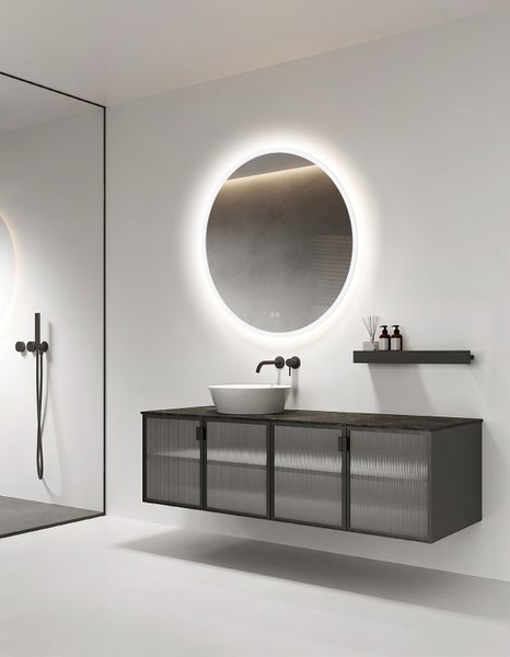 Modernes Badezimmer mit rundem LED-Spiegel, wandhängendem Unterschrank mit geriffelten Glastüren, Aufsatzwaschbecken und dunkler Armatur.
