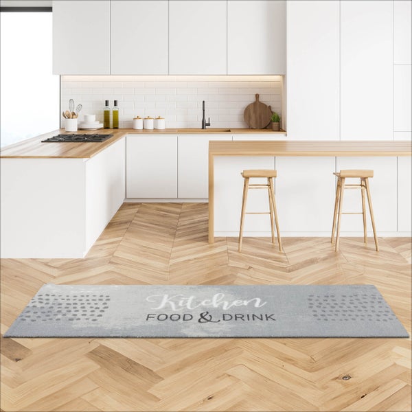 Küchenläufer mit Aufdruck Kitchen Food und Drink auf hellem Fischgrät-Parkett in einer modernen weißen Küche.