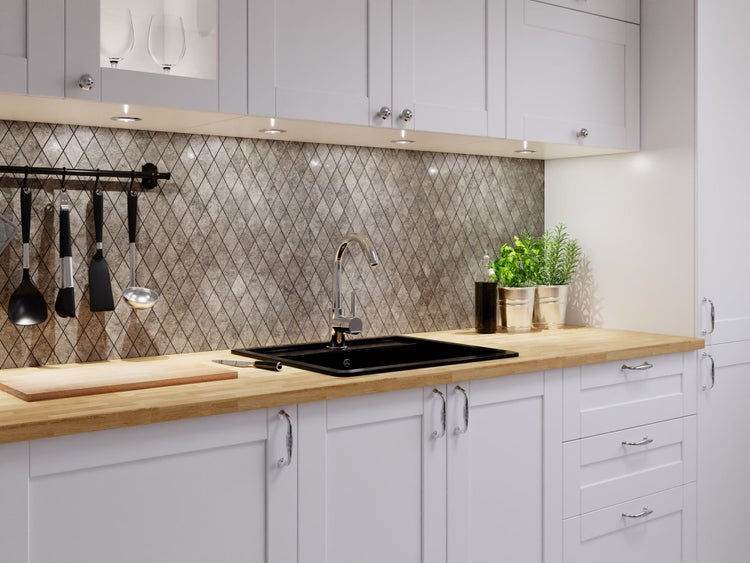 Moderne Küche mit weißen Schränken, Holz-Arbeitsplatte, schwarzer Spüle, Chrom-Armatur und grauem Fliesenspiegel mit Rautenmuster.