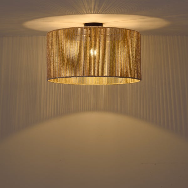 Runde Deckenleuchte mit naturfarbenem Schirm aus Seil-Kordeln, eingeschaltet mit warmem Licht und Schatteneffekt an der Wand.