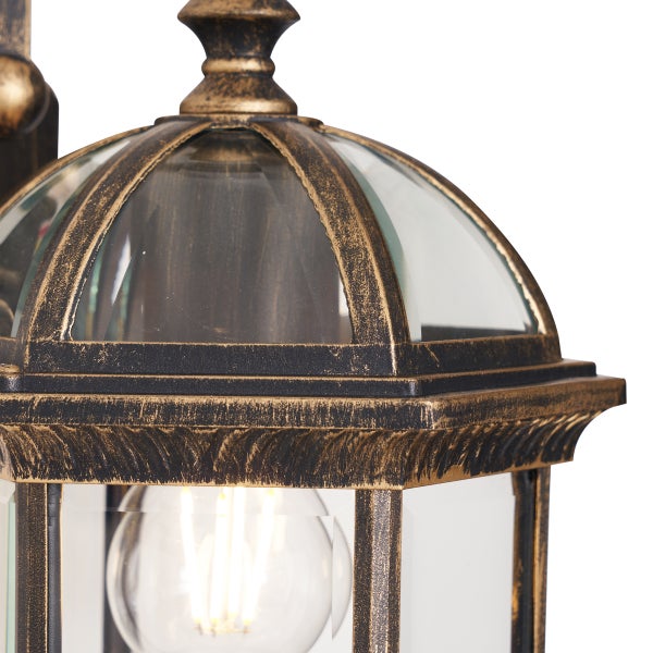 Nahaufnahme einer Außenwandleuchte mit antikem Metallgestell, Glaseinsätzen und einem sichtbaren Leuchtmittel.