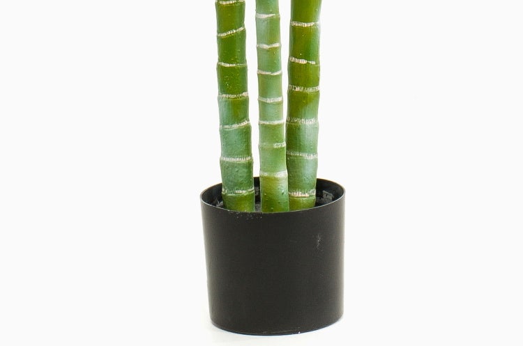 Künstliche Palme mit drei segmentierten Stämmen in schwarzem Topf.