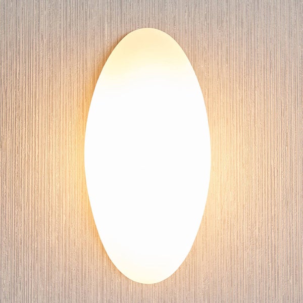 Ovale Wandleuchte mit warmweißem Licht an einer strukturierten Wand.
