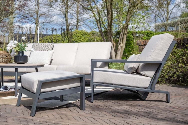 Modernes Lounge-Gartenmöbel-Set aus Metall mit Polstern, bestehend aus Sofa, Sessel, Hocker und Tisch auf einer weitläufigen, organisierten Terrasse.