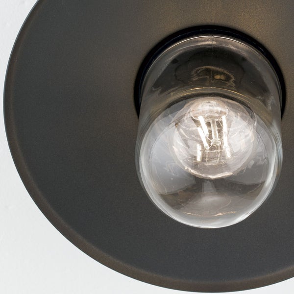 Nahaufnahme eines klaren Filament-Leuchtmittels in einem schwarzen matten Lampenschirm aus Metall.