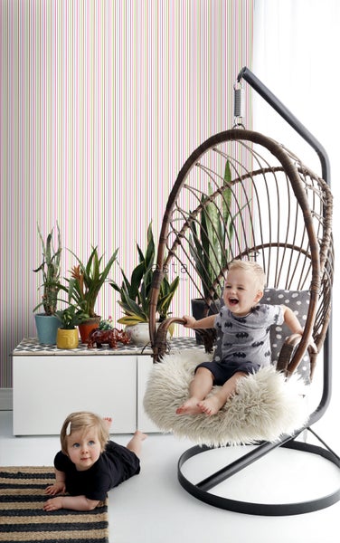 Helles Zimmer mit gestreifter Tapete, Schaukelstuhl und spielenden Kindern