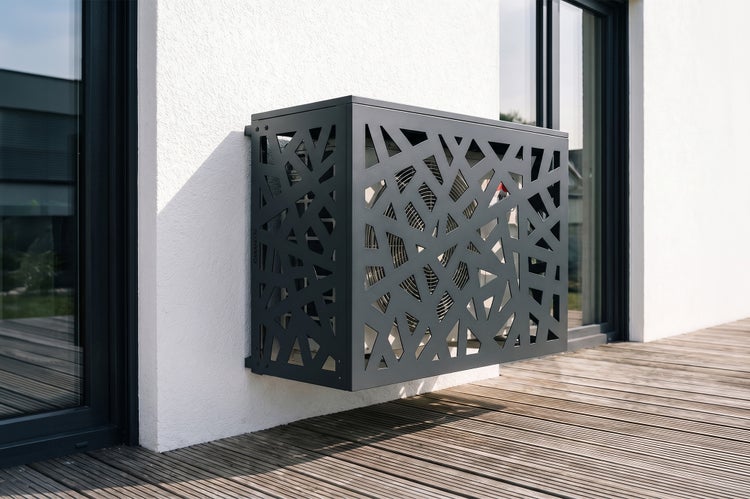 Wandmontierte dekorative Metallverkleidung für Klimaanlagen-Außeneinheiten oder Wärmepumpen mit geometrischem Muster auf einer Terrasse.