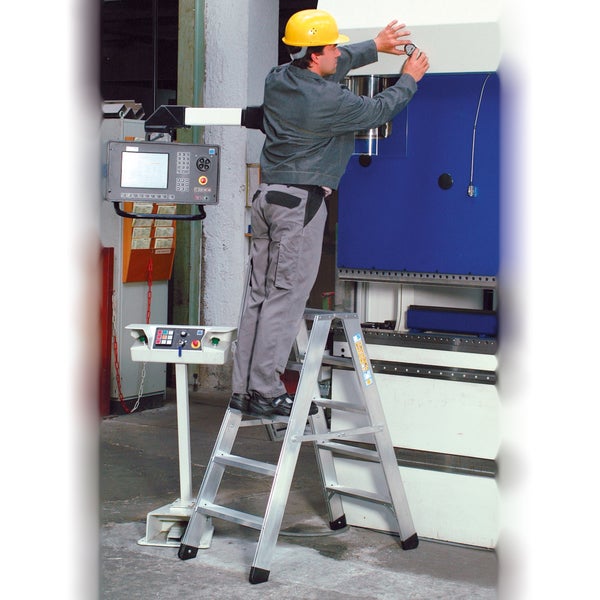 Mann mit Schutzhelm auf einer Aluminium-Stufenleiter bei der Arbeit an einer Maschine