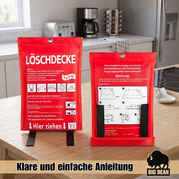 Zwei rote Feuerlöschdecken in einer Aufbewahrungstasche mit Gebrauchsanleitung auf einer Küchenarbeitsplatte.
