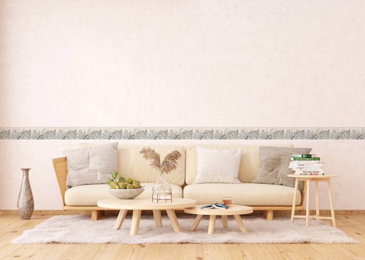 Helles Wohnzimmer mit hellem Sofa, runden Holztischen, flauschigem Teppich und einer Tapetenbordüre mit Blumenmuster.