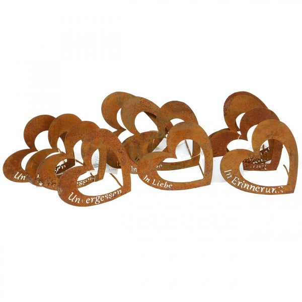 Mehrere rostige Metallherzen mit den Aufschriften 'In Liebe', 'In Erinnerung' und 'Unvergessen'.