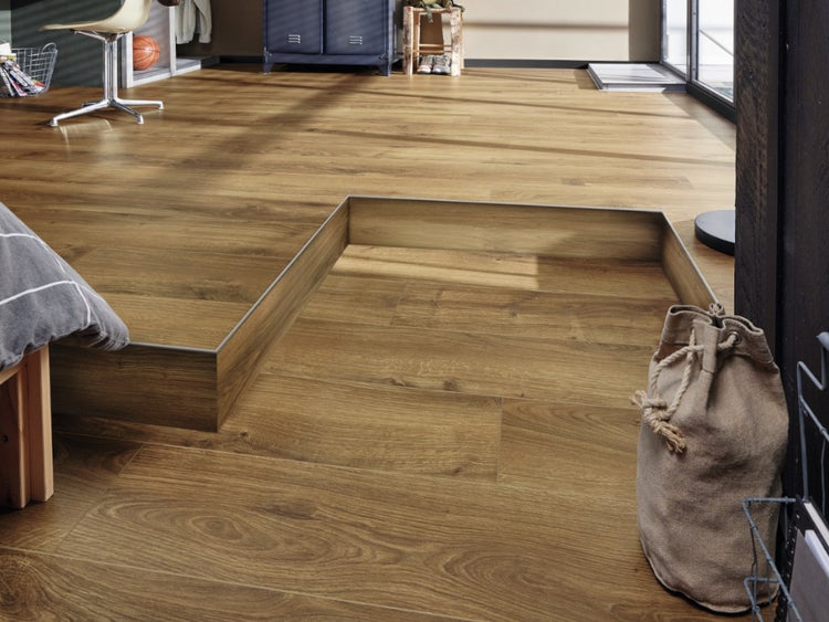 Wohnraum mit Laminatboden in Eichenoptik verlegt auf einer erhöhten Ebene mit Treppenkante und Metallprofilen für einen modernen Übergang.