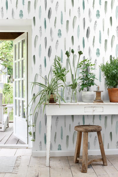 Wohnraum mit Feder-Tapete, Holzhocker und Tisch mit Pflanzen