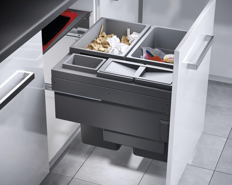 Organisiertes, ausziehbares Mülltrennsystem aus grauem Kunststoff in einem modernen, hellen Küchenunterschrank zur effizienten Abfalltrennung.