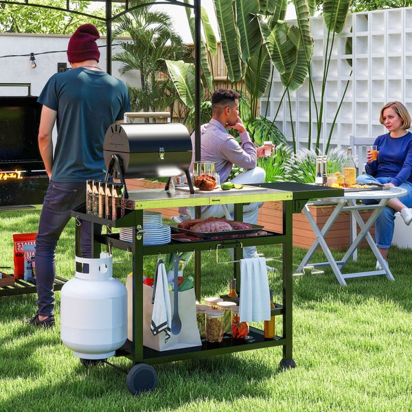 Mobiler Grill-Beistellwagen aus Metall mit Edelstahl-Arbeitsplatte und Ablagefächern in einem hellen Garten mit Personen.