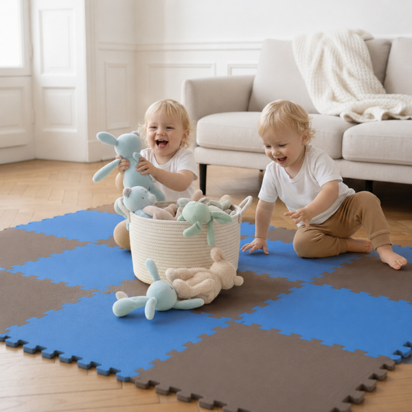 Zwei Kleinkinder spielen auf einer zusammengesetzten Puzzlematte aus Schaumstoff mit Stofftieren und einem Korb im Wohnzimmer
