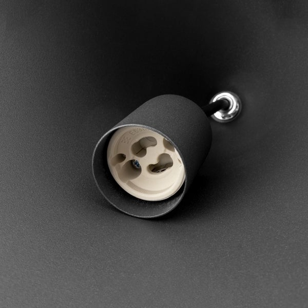 Detailaufnahme einer Lampenfassung für Leuchtmittel mit GU10 Sockel in einer matt schwarzen Lampenabdeckung.