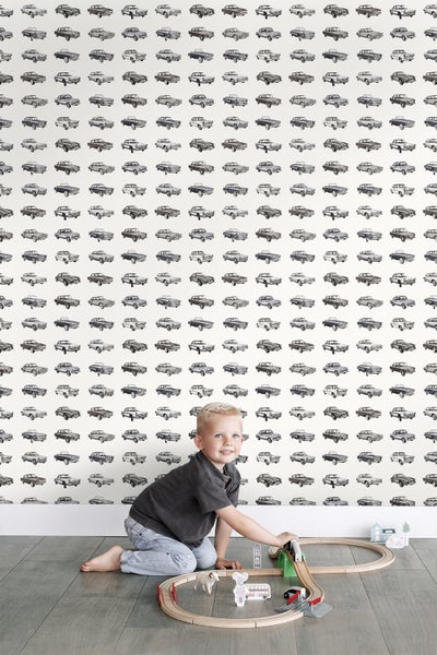 Zimmer mit Auto-Tapete und spielendem Kind mit Holzeisenbahn