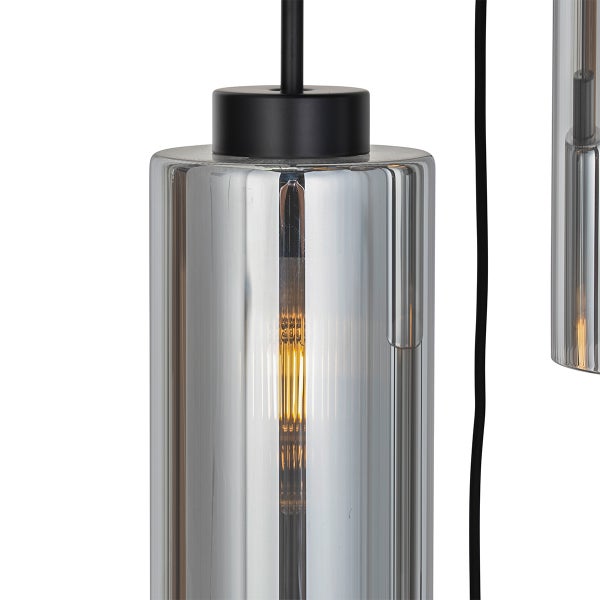 Detailansicht einer Pendelleuchte mit zylindrischem Glasschirm in Rauchglasoptik und eingeschaltetem Filament-Leuchtmittel.