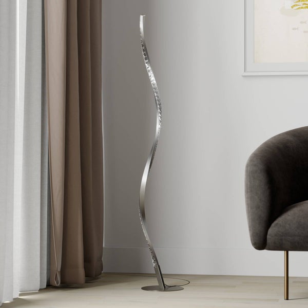 Schlanke, geschwungene LED-Stehleuchte mit Kristalldetails in einem hellen, modern eingerichteten Wohnzimmer mit Sessel und Vorhängen.