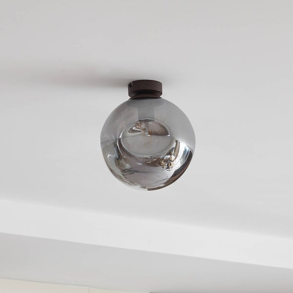 Kugelförmige Deckenleuchte mit einem Schirm aus Rauchglas und einer dunklen Metallhalterung an einer weißen Zimmerdecke.