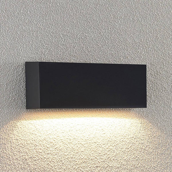 Moderne, schwarze Außenwandleuchte in rechteckiger Form mit nach unten gerichtetem, warmweißem Licht auf einer strukturierten Wand.