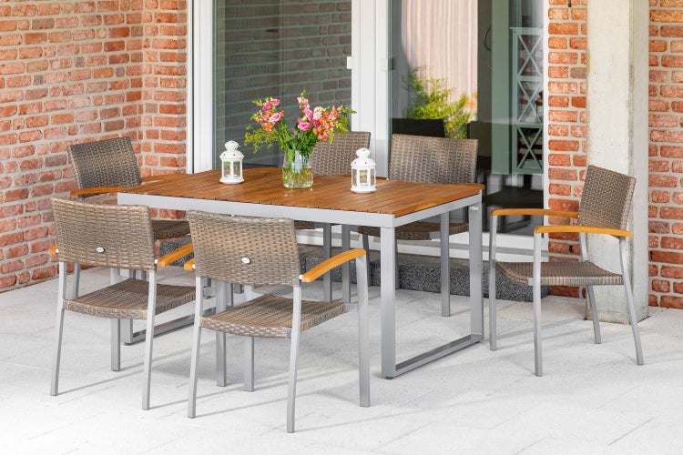 Garten-Essgruppe bestehend aus Holztisch mit grauem Metallgestell und sechs Stühlen mit Geflecht und Holzarmlehnen auf einer Terrasse.