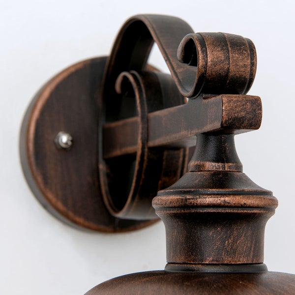 Rustikale Außenwandleuchte aus Metall in Bronze-Optik mit verzierten Schnörkeln im klassischen Design.