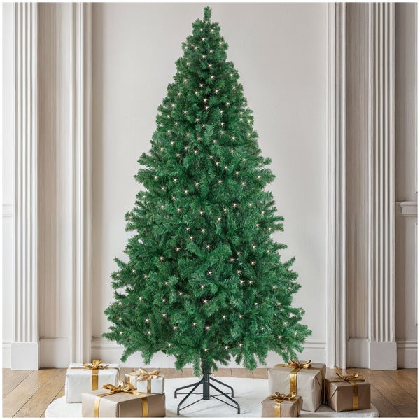 Künstlicher Weihnachtsbaum mit LED Beleuchtung stehend auf einem Metallständer umgeben von Weihnachtsgeschenken in einem Wohnraum