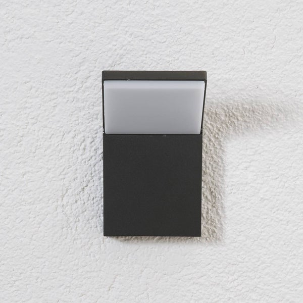Rechteckige Außenwandleuchte in Anthrazit mit weißem Diffusor, montiert an einer strukturierten Wand.