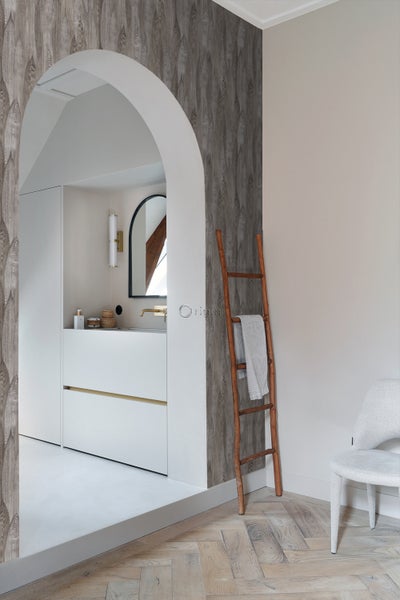 Badezimmer mit gemusterter Tapete in Holzoptik, weißem Waschtisch, Holzleiter und Stuhl