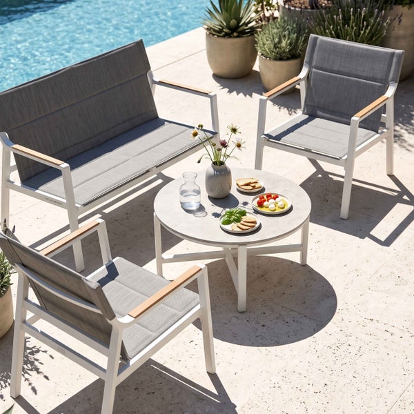 Modernes Garten-Lounge-Set mit Zweisitzer-Sofa, zwei Sesseln und rundem Tisch auf einer hellen Terrasse neben einem Pool.