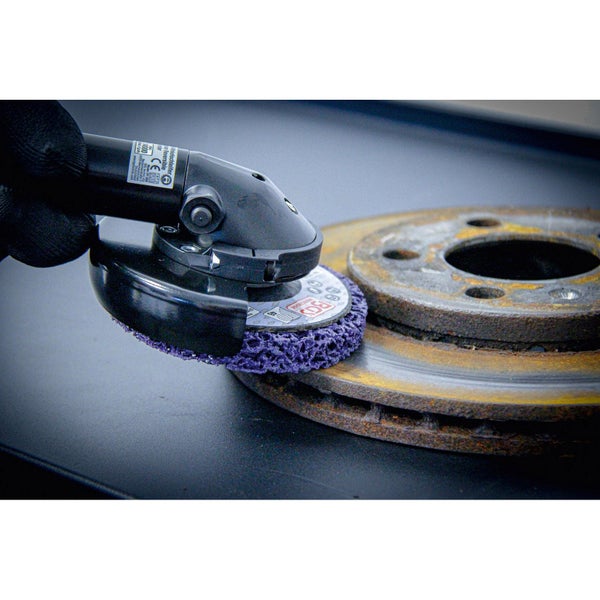 Bohrmaschine mit Schleifscheibe beim Schleifen einer Bremsscheibe