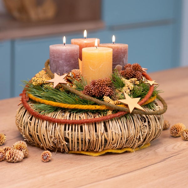 Adventskranz mit vier brennenden Kerzen, Tannenzweigen, Sternen und Zapfen