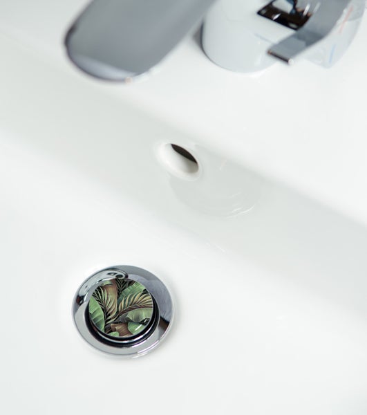 Detailaufnahme eines Waschbeckens mit floralem Abflussstopfen und Armatur