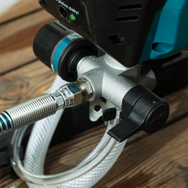 Nahaufnahme eines Airless-Farbsprühgeräts mit Metallverteiler, flexiblem Schlauchanschluss und schwarzem Schalthebel.