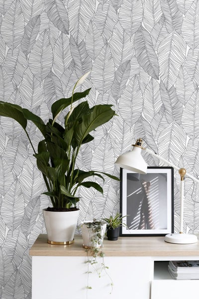 Zimmer mit gemusterter Tapete, Tisch, Lampe und Pflanzen