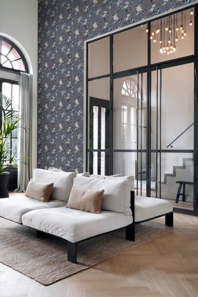 Wohnzimmer mit floral gemusterter Tapete, Sofa und Glastür