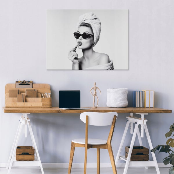 Wandbild mit Motiv einer Frau mit Sonnenbrille und Handtuch über dem Schreibtisch in einem modernen Heimbüro.