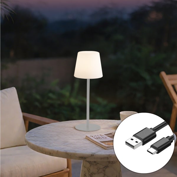 Moderne kabellose LED-Tischleuchte auf einem Marmortisch im Garten bei Dämmerung, inklusive USB-Ladekabel.