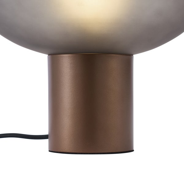 Moderne Tischleuchte mit bronzefarbenem zylindrischem Metallfuss und mattem Glasschirm in der Nahaufnahme.