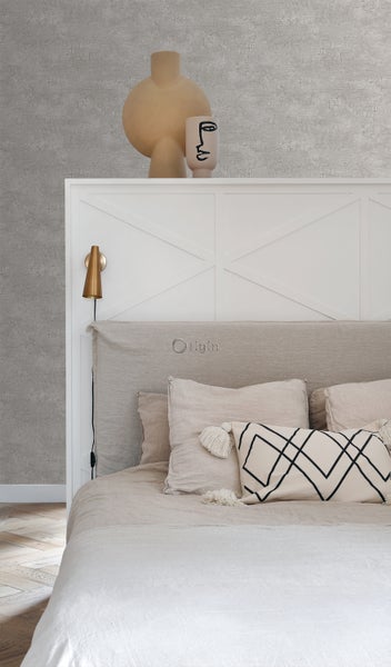 Schlafzimmer mit Bett, Kissen und Dekorationsartikeln auf dem Kopfteil