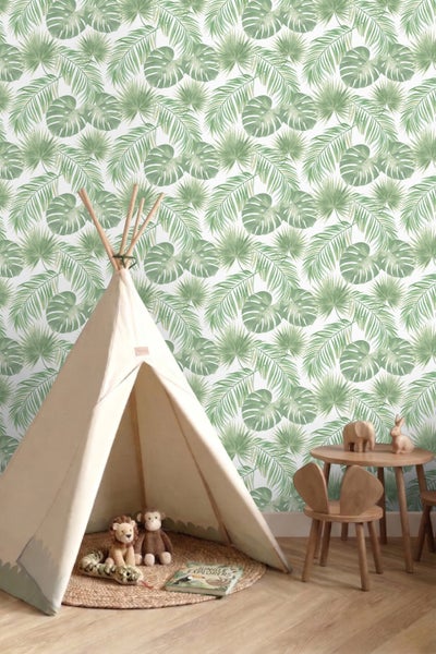 Kinderzimmer mit Tapete im tropischen Blattmuster, einem Tipi-Zelt aus Stoff, einem Holztisch mit Stühlen und Kuscheltieren.