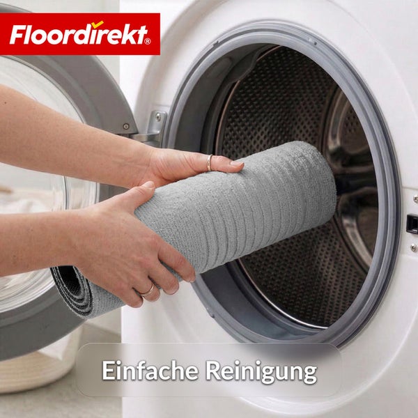 Ein zusammengerollter Teppich wird zur einfachen Reinigung in eine Waschmaschine gelegt. Floordirekt Logo.