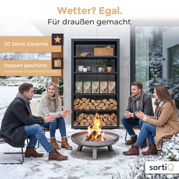 Zwei Paare sitzen im verschneiten Garten vor einer SortiQ Kaminholzregal mit brennender Feuerschale, eloverzinkt und pulverbeschichtet.