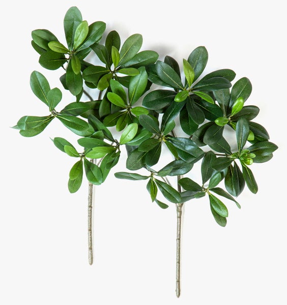 Künstliche grüne Blätter einer Kunstpflanze in der Nahaufnahme mit sichtbarer Blattstruktur.