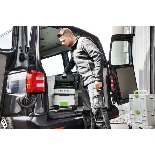 Ein Handwerker verlädt einen Industriesauger in einen Transporter.